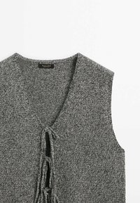 Gray knitted sleeveless top with a V-neck, features a tie closure at the front, and a textured fabric pattern throughout.