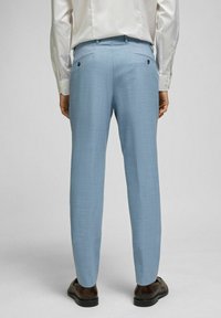 Lichtblauwe op maat gemaakte broeken met een gestructureerde stof, voorzien van twee achterzakken en een slim fit. Gestyled met donkere schoenen.