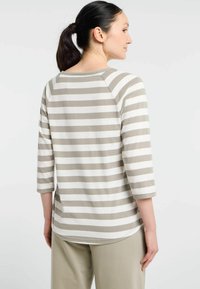 Gestreiftes Langarmoberteil in hellem Beige und Off-White, mit einem runden Halsausschnitt und drei Viertel-Raglanärmeln. Aus weichem Baumwollstoff.