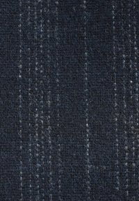 Donkerblauwe textiel met een gestructureerd oppervlak en lichtere strepen, gemaakt van geweven vezels. De algehele uitstraling is gemarmerd en licht fuzzy.