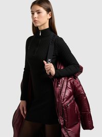 Zwarte geribde jurk met een hoge hals, gecombineerd met een glanzend bordeauxrood donzen jack. Voorzien van ritsen en verstelbare banden.