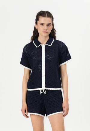 Navy knitted two-piece set featuring a short-sleeved top with white trim and button closure, paired with matching shorts, both with a mesh texture.