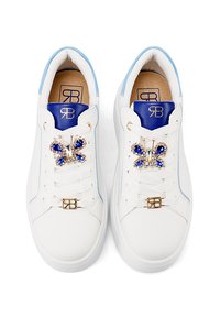 Sneakers bianchi con accenti blu. Design con lacci che presenta una farfalla decorativa con ornamenti blu e trasparenti sulla linguetta.