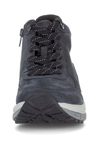 Zwarte sportieve schoen met reflecterende stippenveters, gepolsterde kraag, zijdelingse rits en geribbelde wit-zwarte rubberen zool, gezien vanuit de voorkant.