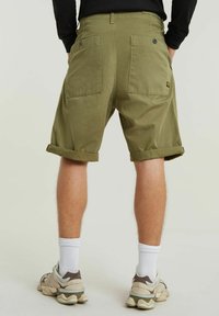 Pantaloni corti verde oliva con risvolti, due tasche posteriori e chiusure a bottone. Realizzati in tessuto resistente, adatti per un abbigliamento casual.