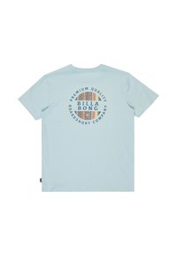 T-shirt azzurra chiara con maniche corte, caratterizzata da una grafica circolare al centro con motivi e il testo "BILLA BONG" e "QUALITÀ PREMIUM."