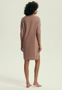 Różowa sukienka o długości do kolan, oversize, wykonana z miękkiego materiału. Posiada rękawy o długości do łokcia i prosty, okrągły dekolt.