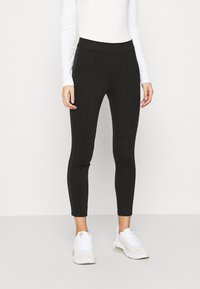 Svarta leggings med hög midja, tillverkade av slät, elastisk tyg. De har sömmar framtill och en åtsittande siluett.