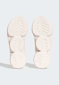 Semelles de chaussures de sport blanches avec tread texturé, dotées d'un design segmenté et de bords incurvés pour améliorer l'adhérence et la flexibilité.