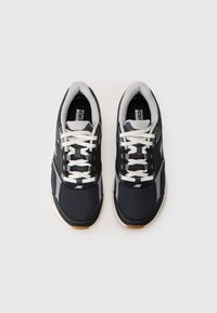 Sæt af sorte og grå Skechers sportsko med hvide snører og polstrede kraver, vist side om side på en hvid baggrund.
