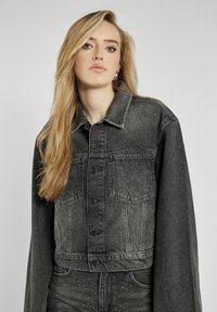 Czarna, skórzana kurtka o skrojonym kroju z oversize'owymi rękawami, dwiema kieszeniami na piersi i subtelnymi srebrnymi drobinkami. Zapięcie na guziki z klasycznym kołnierzem.