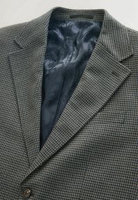 Textured blazer in a houndstooth pattern of brown and navy. Satin interior lining in dark blue with wavy pattern. Single button closure.