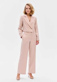 Lichtroze cropped blazer met dubbele knopen, gecombineerd met hoge taille, wijde broekspunten. Glad materiaal met een strakke silhoeët.