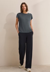 Dark gray T-shirt with short sleeves, paired with wide-leg navy pants. Shoes are light-colored with a textured finish. Simple, relaxed fit.