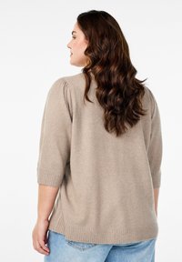 Maglione lavorato a maglia beige con maniche a sbuffo corte, polsini e orlo a coste. Texture morbida, vestibilità rilassata e scollatura arrotondata.
