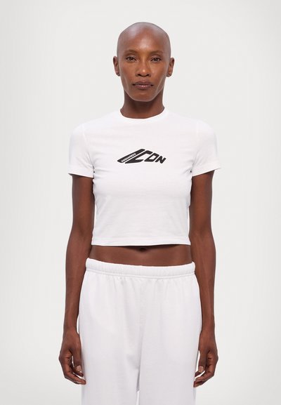 T-shirt blanc court en tissu lisse, avec un design de logo imprimé noir sur la poitrine, des manches courtes et une silhouette ajustée.