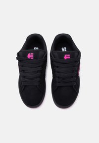 Ζευγάρι μαύρα αθλητικά παπούτσια με ροζ λογότυπο στη γλώσσα και στις πλευρές, μαύρα κορδόνια και επενδεδυμένο περιλαίμιο, εμφανιζόμενα από πάνω σε λευκό φόντο.