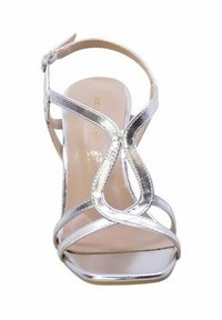 Sandali con tacco alto in argento, presentano un design con cinturini, punta aperta e un accento curvo nella parte anteriore. Il materiale ha una finitura lucida.