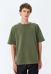 Olivenfarvet t-shirt med korte ærmer i en afslappet pasform, lavet af blød bomuld. Har en rund halsudskæring og minimalt syning.
