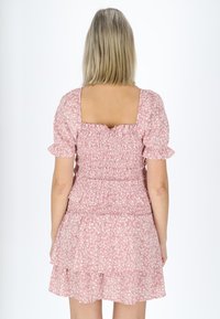 Lyserød blomsterkjole med puffede ærmer, firkantet ryg og en lagdelt nederdel med samlet detaljering langs bodice og talje.