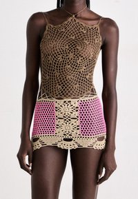 Le body en crochet présente une couleur beige avec des motifs floraux complexes, complétés par des accents roses sur la partie inférieure. Léger et texturé.