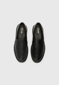 Černé kožené slip-on boty s kulatou špičkou, prošívanými detaily a embosovaným páskem. Plná podrážka a polstrovaná stélka pro pohodlí.