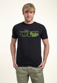 Černé bavlněné tričko s žlutým a modrým logem s nápisem "JT Racing USA." Kulatý výstřih a krátké rukávy.