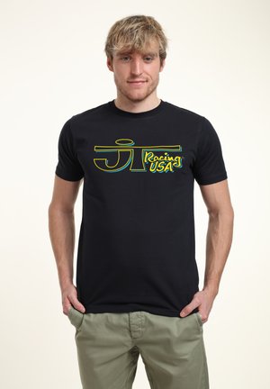 Černé bavlněné tričko s žlutým a modrým logem s nápisem "JT Racing USA." Kulatý výstřih a krátké rukávy.