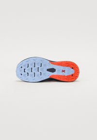 Melnas sporta kurpes zole ar zilu un oranžu gumijas ārējo zoli, kas apgādāta ar strukturētu saķeres rakstu un centrā esošu logo detaļu.