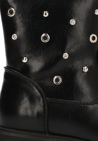 Botín de cuero negro con tachuelas metálicas circulares y rhinestones de distintos tamaños, con una textura suave y suela de goma.