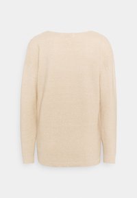 Beige stickad tröja med lös passform, vid halsringning, ribbade ärmslut och fåll, med en texturerad yta utan synliga mönster eller detaljer.