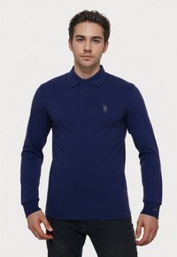 Polo shirt a maniche lunghe blu navy realizzato in tessuto morbido, con colletto, pattina con tre bottoni e logo dorato sul petto.