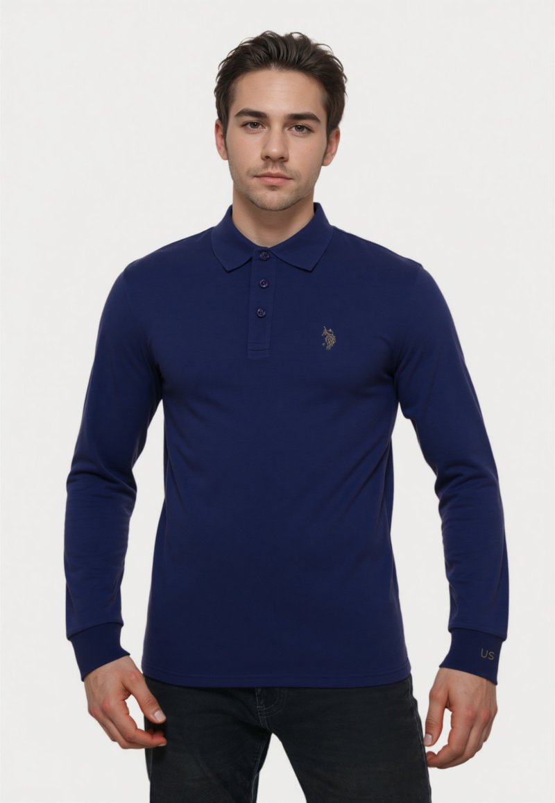 Polo shirt a maniche lunghe blu navy realizzato in tessuto morbido, con colletto, pattina con tre bottoni e logo dorato sul petto.