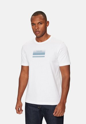 Camiseta de algodón blanca con cuello redondo. Presenta un gráfico rectangular en degradado azul con el texto "Calvin Klein" centrado en el frente.