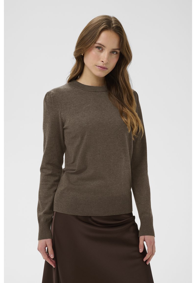 Brauner, gestrickter Pullover mit langen Ärmeln und gerippten Bündchen. Verfügt über einen runden Ausschnitt und einen figurbetonten unteren Saum, getragen über einem braunen Satinhrock.