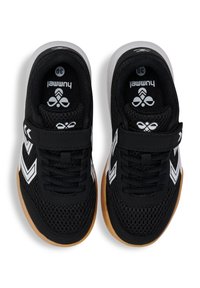 Des chaussures de sport noires avec une tige en maille, des accents blancs en zigzag, une bande Velcro et une semelle en caoutchouc naturel. Étiquette de taille visible à l'intérieur.
