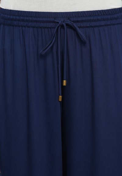 Navy blue lightweight pants with an elastic waistband, drawstring with gold metal tips, and smooth fabric texture. Casual design.
