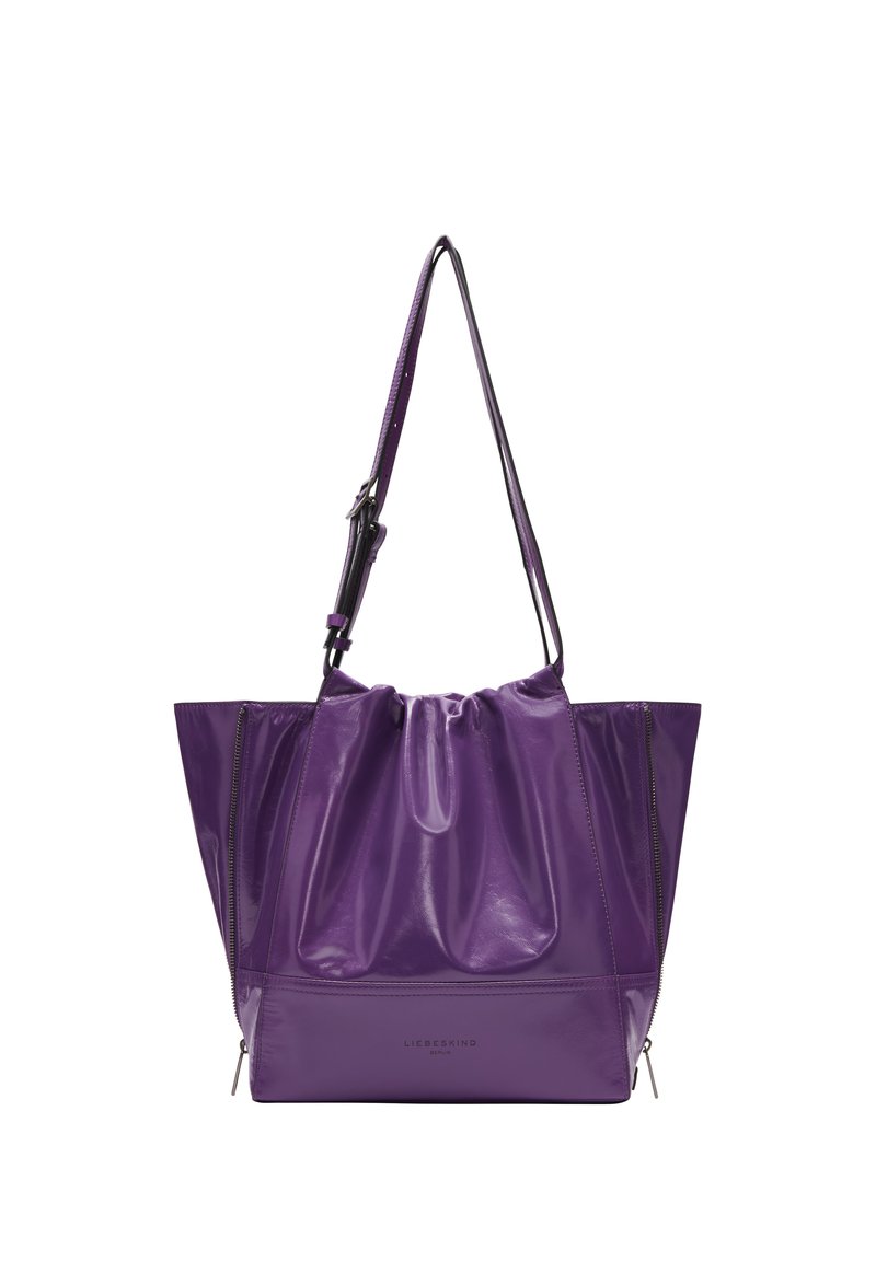Sac fourre-tout en cuir verni violet avec un dessus resserré, des côtés zippés doubles et une bandoulière détachable. Texture lisse, forme structurée.