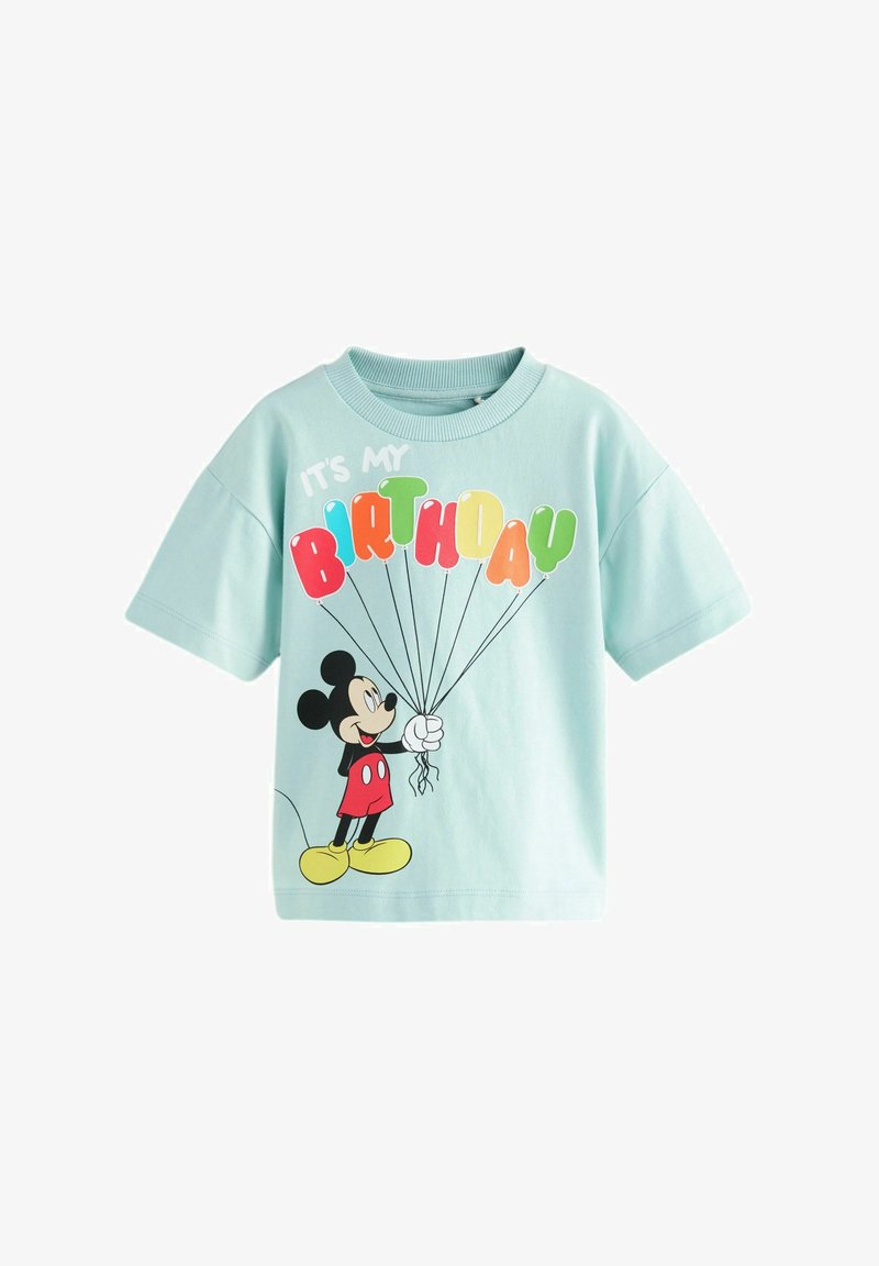 Gaiši zils kokvilnas T-krekls ar karikatūras varoni, kurš tur krāsainus balonus, un uzrakstu "MAN IR DZIMŠANAS DIENA."