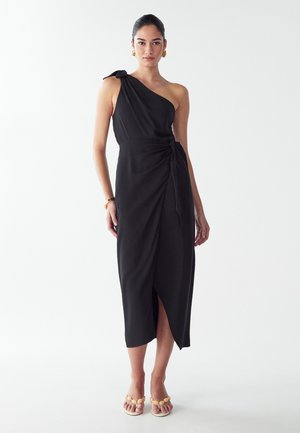 Čierne šaty s jedným ramienkom, s detailom viazania v páse, asymetrickým lemom a rozparkom po stehná. Tkanina je jemná a elegantne padne.