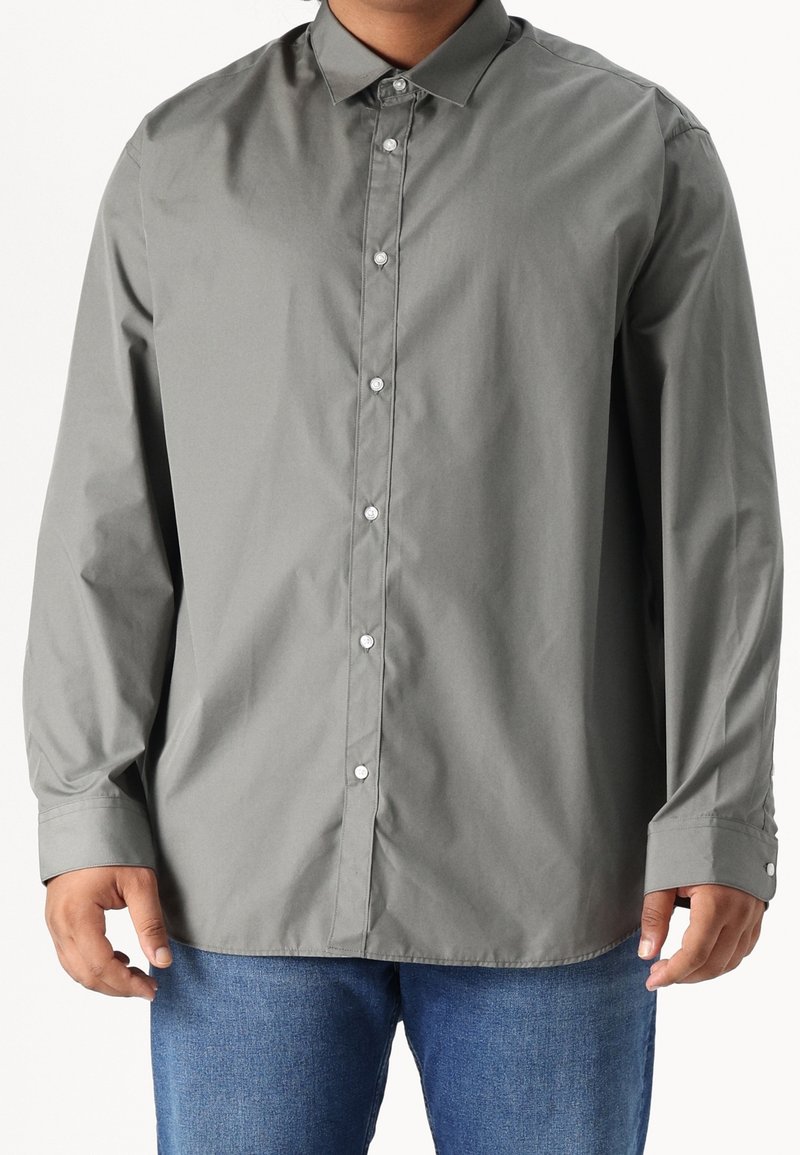 Camisa abotonada gris claro en mezcla de algodón, con cuello clásico, mangas largas y puños abotonados, con una textura suave y ligeramente brillante.