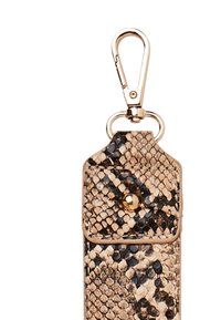 Brelok do kluczy z nadrukiem wężowej skóry z elementami w złotym kolorze. Posiada fakturowaną powierzchnię, zapięcie na zatrzask oraz klamrę na górze.