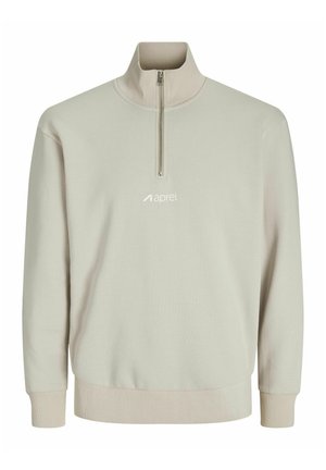 Sweatshirt zippé beige clair en demi-fermeture, fabriqué en tissu doux, avec des poignets côtelés et un logo brodé sur la poitrine. Texture lisse.