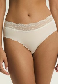 Białe majtki z koronkową lamówką o falistych krawędziach, gładkim materiale i średnim stanie, posiadające delikatny teksturowany pas w talii.