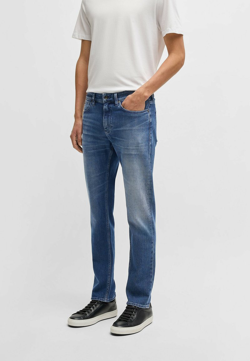 Denimjeans i medelblå tvätt med rak bendesign, med en klassisk femfickestil och en subtil blekningseffekt.