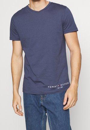 Granatowy bawełniany t-shirt z dekoltem w serek, krótkimi rękawami oraz białym logo z czerwonymi i niebieskimi akcentami na dole.