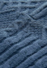 Tessuto a maglia di un profondo blu navy, con un motivo in rilievo e trame intrecciate. Superficie morbida e pelosa con una profondità pronunciata.