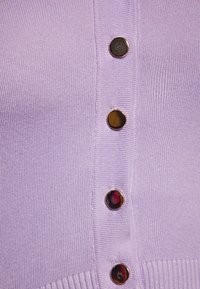 Cardigan lavorato a maglia lilla con una fila di cinque bottoni rotondi scuri al centro, con una texture a costine all'orlo e lungo le Bande dei bottoni.