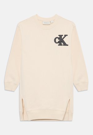 Sweatshirt beige clair à manches longues, avec des fentes sur les côtés et un logo "ck" texturé en noir sur la poitrine gauche. Matière en coton douce.