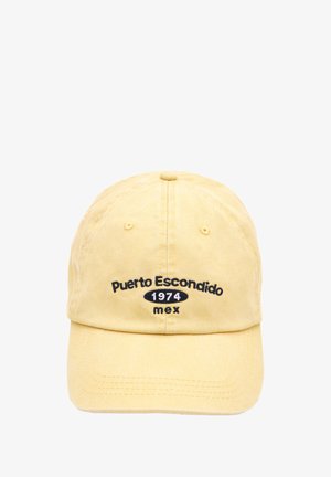 Gul bomulds hat med broderet tekst "Puerto Escondido 1974 mex" i sort, med en buet skygge og justerbar rem bagpå.